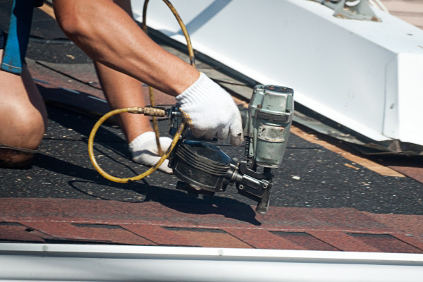Expert roofer performing scheduled roof maintenance repairs to asphalt shingles